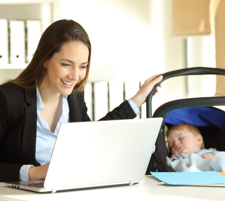 mom uses computer with baby next to her